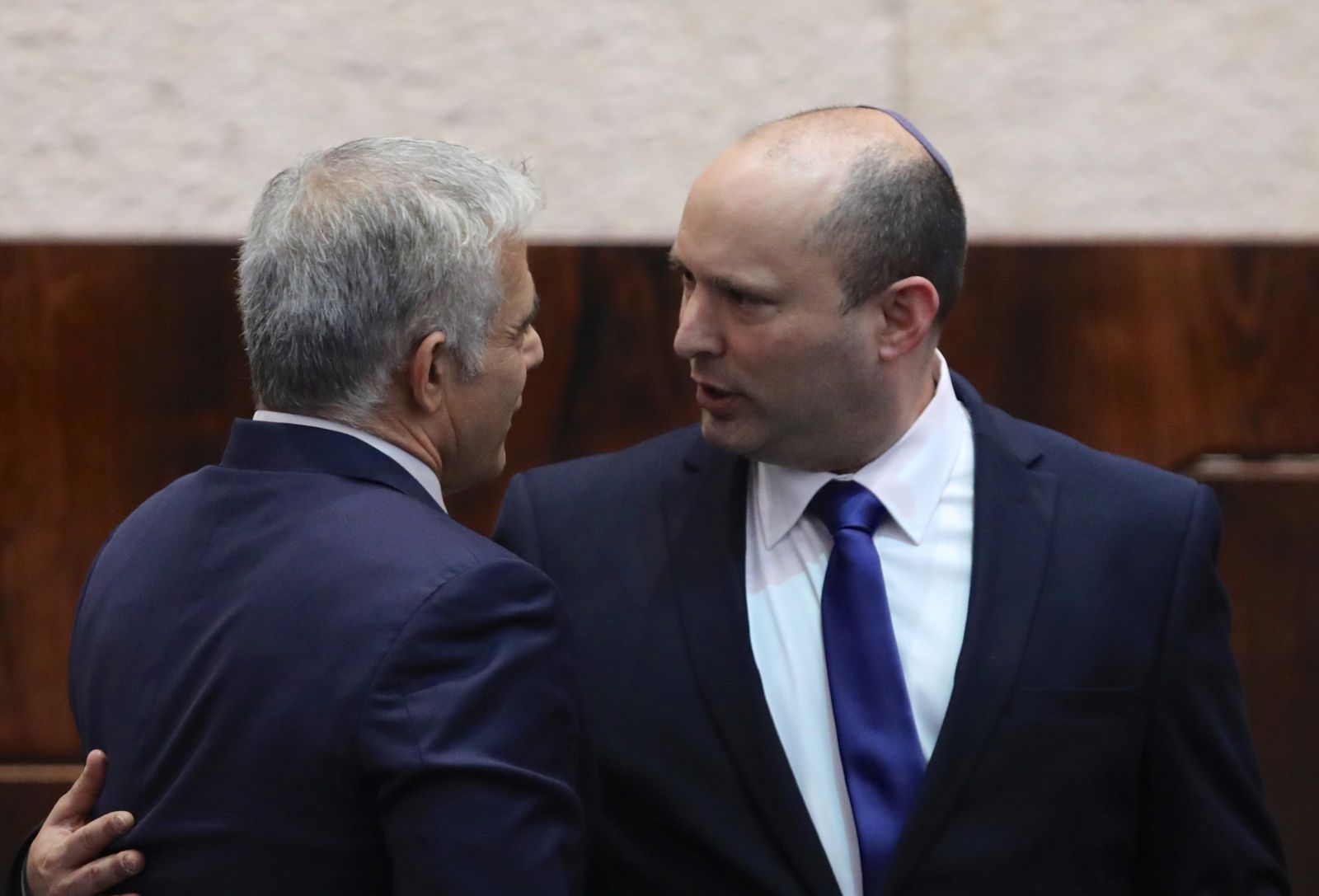 epa09267664 Leader of the Yemina party and designated prime minister Naftali Bennett  (R) embraces his political partner Yair Lapid (L) during a special voting session on the formation of a new coalition government at the Knesset Plenum, at the Knesset, Israeli parliament, in Jerusalem, Israel, 13 June 2021.The Knesset is convening for a vote that is expected to end the historic 12-year rule of Prime Minister Benjamin Netanyahu.  EPA/ABIR SULTAN