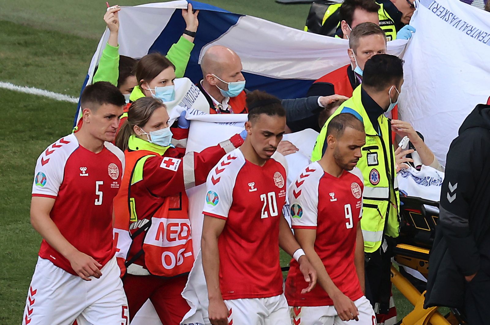 epa09265524 Players of Denmark escort their teammate Christian Eriksen as he is stretchered off the pitch after receiving medical assistanceduring the UEFA EURO 2020 group B preliminary round soccer match between Denmark and Finland in Copenhagen, Denmark, 12 June 2021.  EPA/Wolfgang Rattay / POOL (RESTRICTIONS: For editorial news reporting purposes only. Images must appear as still images and must not emulate match action video footage. Photographs published in online publications shall have an interval of at least 20 seconds between the posting.)