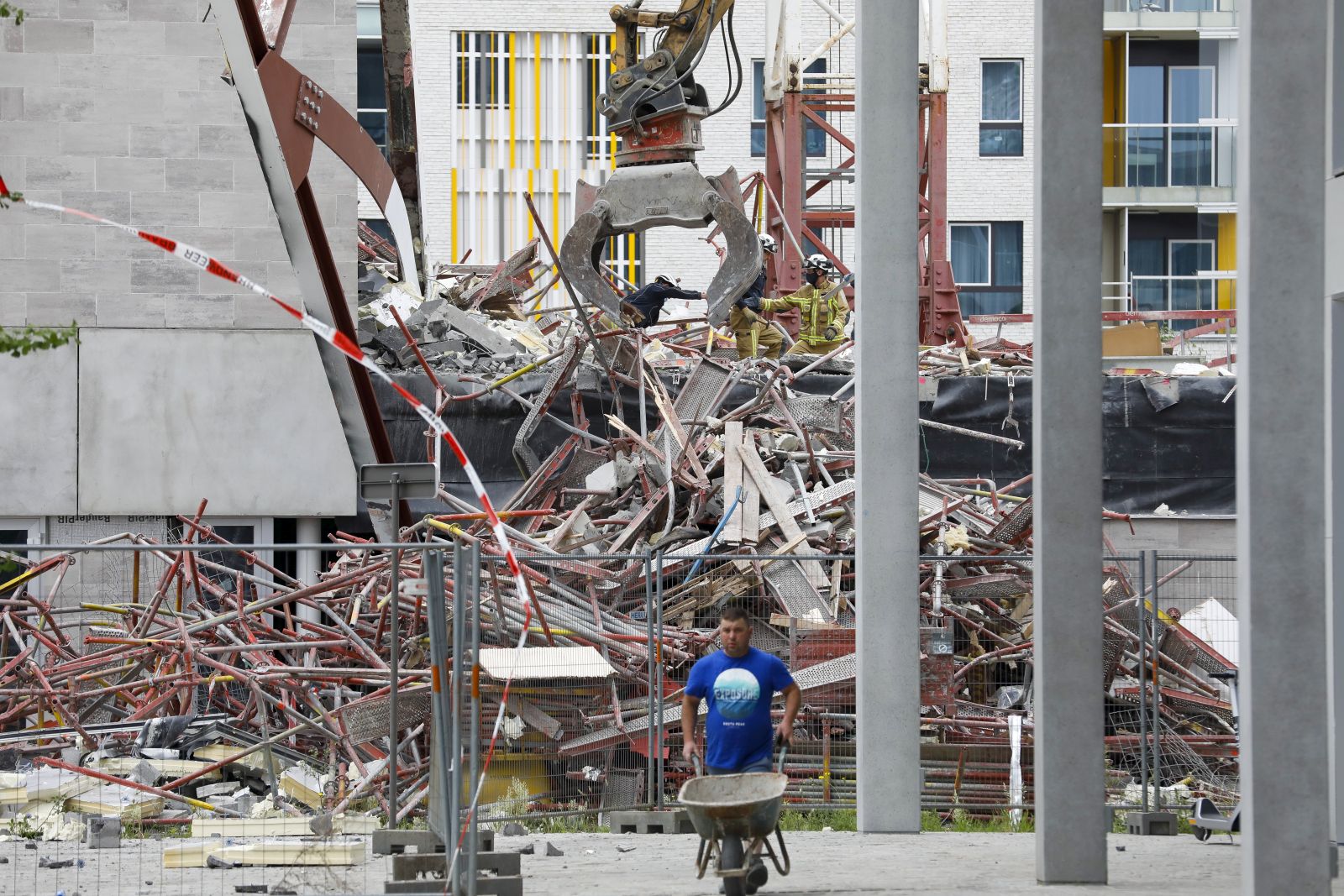 epa09284873 Firefighters work in the rubbles of a building that partially collapsed, killing at least two persons in the 'Nieuw Zuid' quarter in Antwerp, Belgium, 19 June 2021. At least two people were killed and dozens have been injured after a building that was under construction collapsed on a building site in the Nieuw Zuid area of Antwerp.  EPA/JULIEN WARNAND