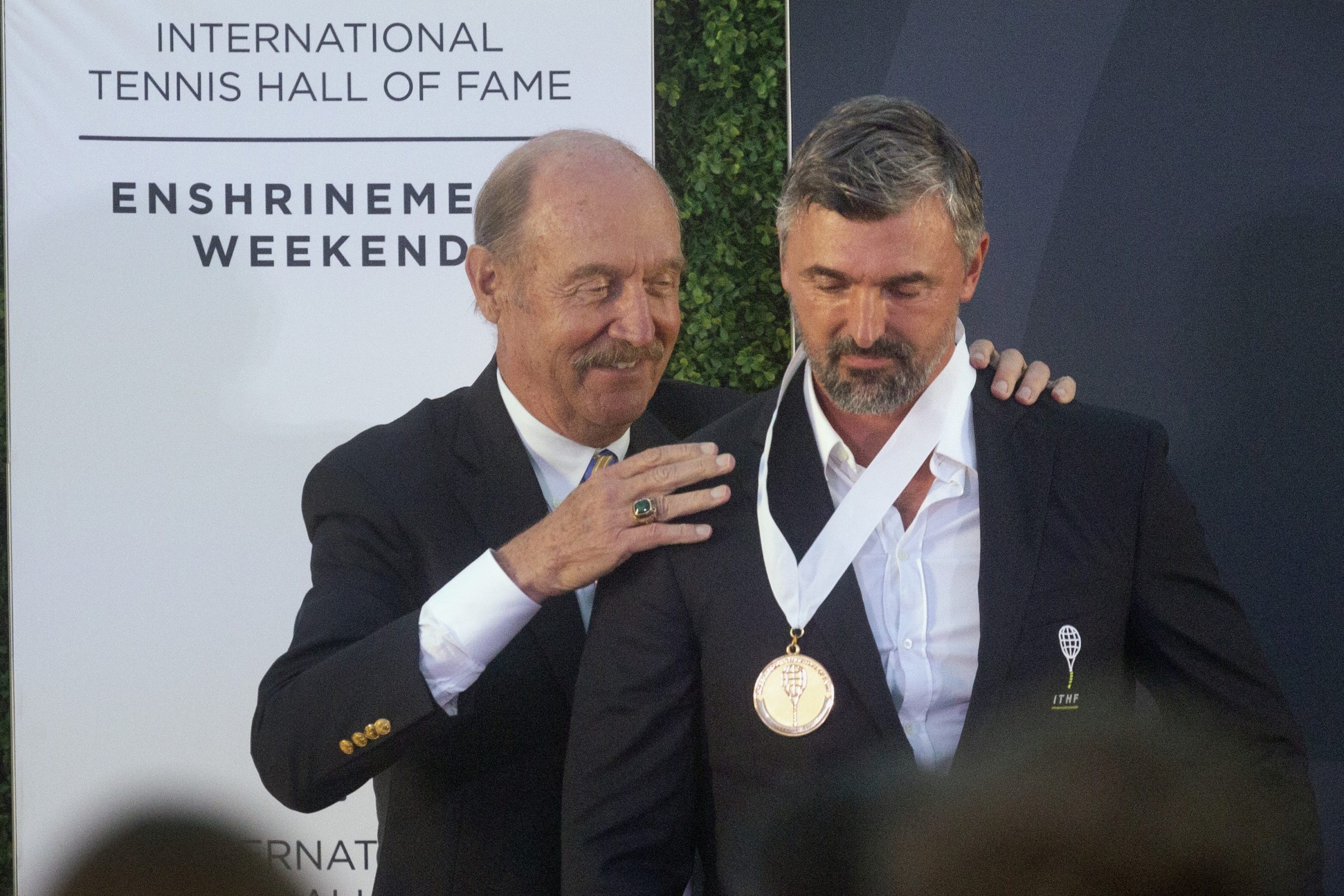 Stan Smith, left, president of the International Tennis Hall of Fame, inducts Goran Ivanisevic into the hall Saturday, July 17, 2021, in Newport, R.I. (AP Photo/Michael Dwyer)