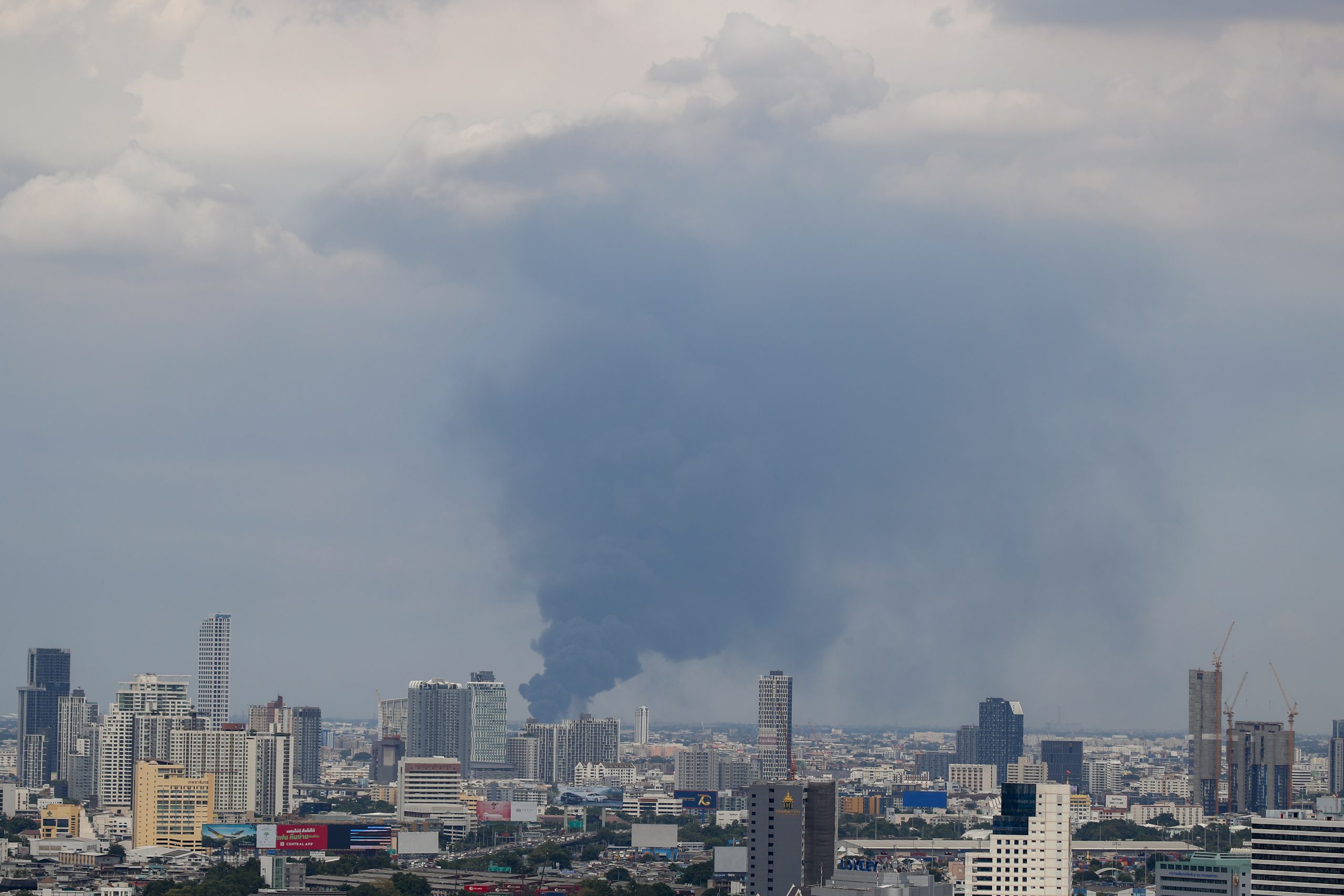 epa09323237 Black smoke billows among tall buildings following an explosion at a factory in Samui Prakan, Thailand, 05 July 2021. An explosion followed by a fire destroyed a factory producing plastic foam and plastic pellets in Bang Phli district of Samut Prakan, injuring at least 21 people according to officials. The explosion caused damage to surrounding buildings, and the Disaster Prevention and Mitigation Department has advised residents in a 5 kilometer radius to evacuate until further notice.  EPA/DIEGO AZUBEL