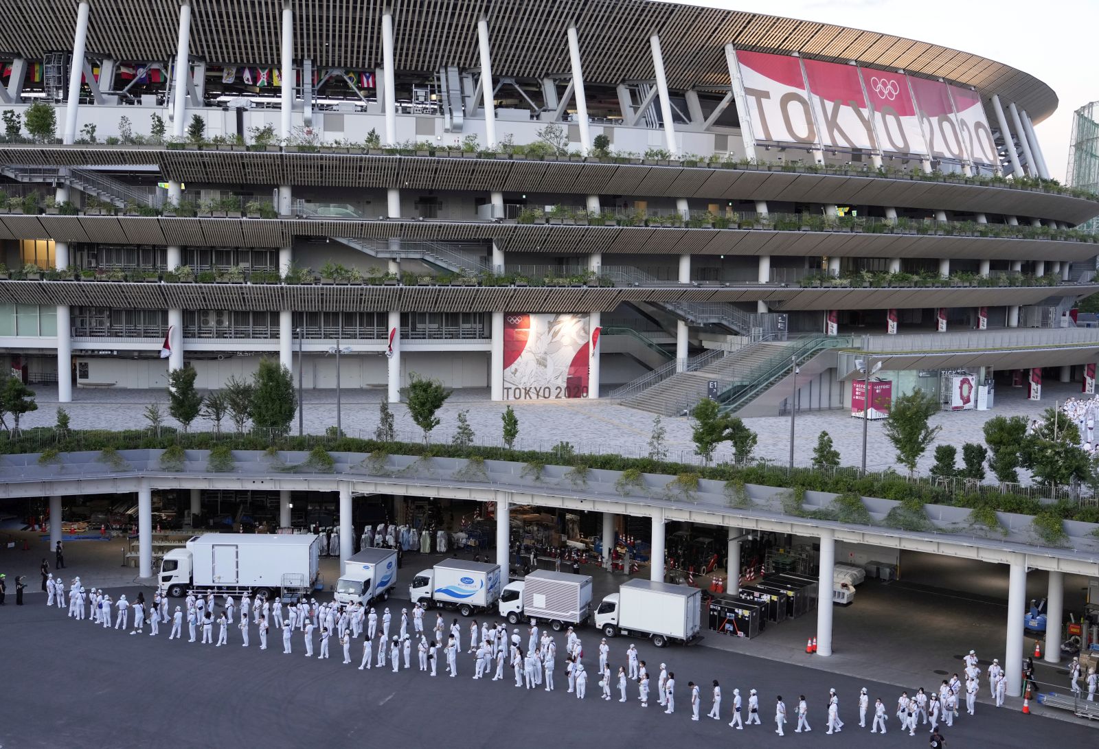 epa09351550 Staff members gather around the National Stadium, the main venue of the Tokyo 2020 Olympics and Paralympics, ahead of the opening ceremony of the Tokyo 2020 Games in Tokyo, Japan, 18 July 2021. Just five days before the opening of the Tokyo Games, latest polls show that a major part of the population is concerned about the the Olympics as Tokyo recorded 1,000 new COVID-19 cases for the fifth straight day.  EPA/FRANCK ROBICHON