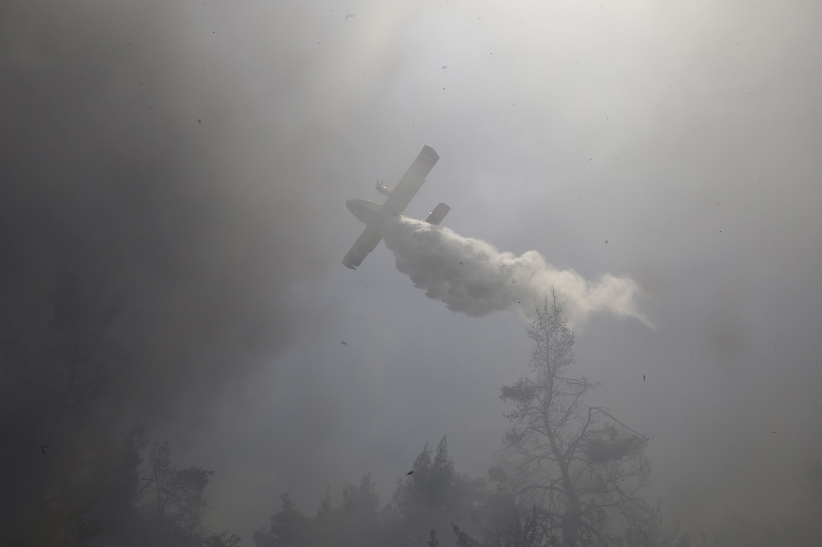 epa09370847 A firefighting aircraft douses a wildfire in the area of Stamata, in north-eastern Athens, Greece, 27 July 2021. Firefighting forces are operating in the area of Stamata, in the Attica region, to contain a wildfire that broke out earlier in the day. Some 22 fire engines with 68 crew members, three teams of firemen on foot, the municipality's water trucks along with four firefighting aircraft, and five water dropping helicopters are currently battling the blaze which is very close to inhabited areas. In the meanwhile, the Civil Protection's emergency number 112 was activated in the wider region of Stamata and Rodopoli informing the citizens to be on alert and follow authorities' instructions.  EPA/YANNIS KOLESIDIS