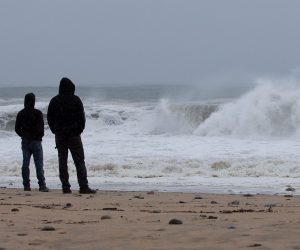 epa09424725 Onlookers watch the waves churned up by Tropical Storm Henri at Misquamicut Beach n Westerly, Rhode Island, USA, 22 August 2021. Tropical Storm Henri is expected to make landfall near the Connecticut and Rhode Island boarders later in the day.  EPA/CJ GUNTHER