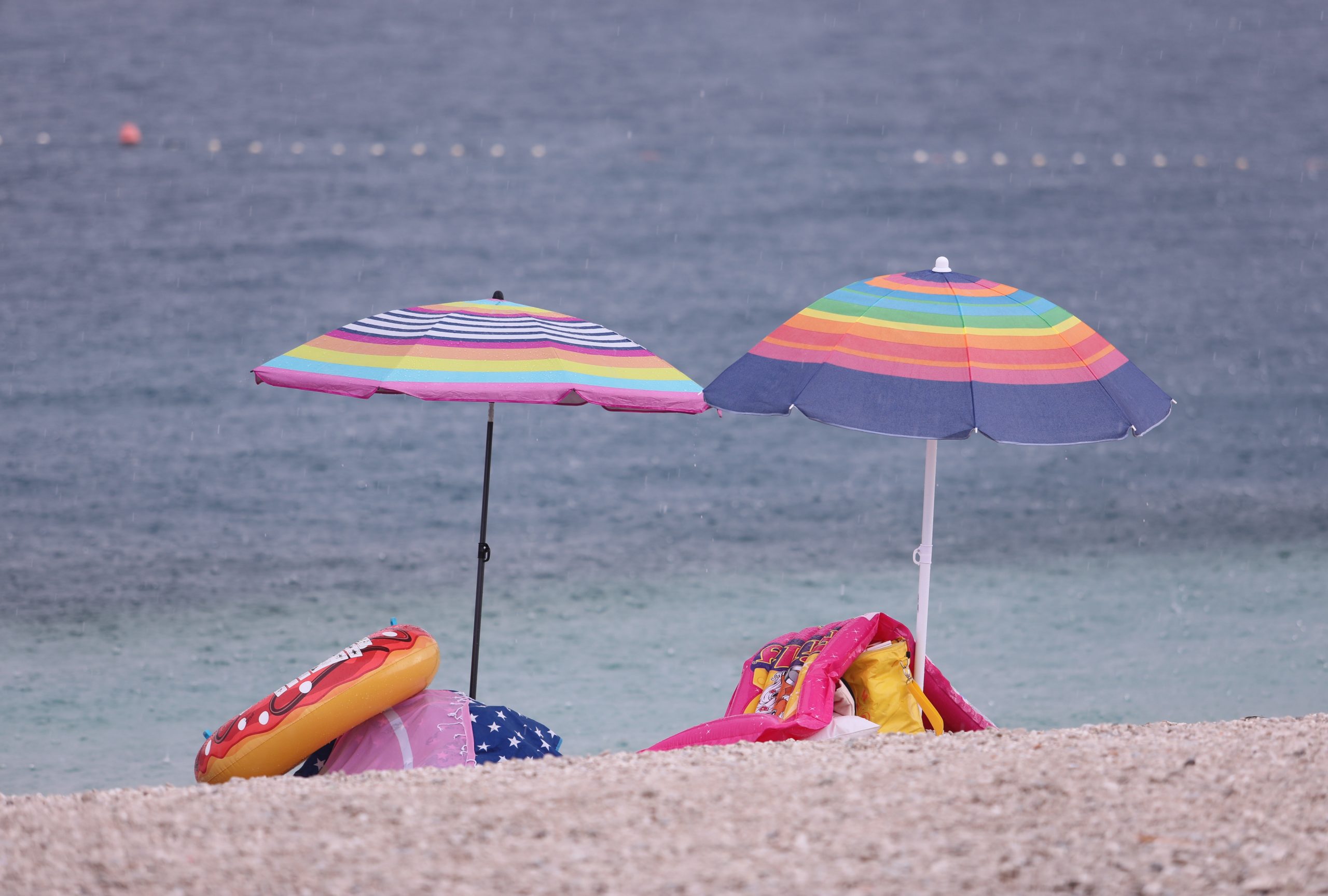 17.08.2021., Split - Kratkotrajni pljusak pracen vjetrom potjerao kupace s plaze Znjan. Oni hrabriji ostali su pod suncobranima, a neki su nastavili uzivati u kupanju s sodatnim osvjezenjem.
Photo: Ivo Cagalj/PIXSELL