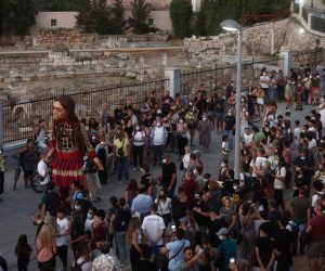 epa09443610 A giant puppet of a young refugee girl Amal walks on a pedestrian street of Ermou with people around of her in Athens, Greece, 02 September 2021. The 3.5 meter-tall artwork of a young Syrian refugee child will walk across Turkey, Greece, Italy, France, Switzerland, Germany, Belgium and the UK to focus attention on the urgent needs of young refugees. A giant puppet of a young refugee girl is part of 'The Walk,' an art initiative that will travel 8,000 kilometers in support of refugees.  EPA/YANNIS KOLESIDIS