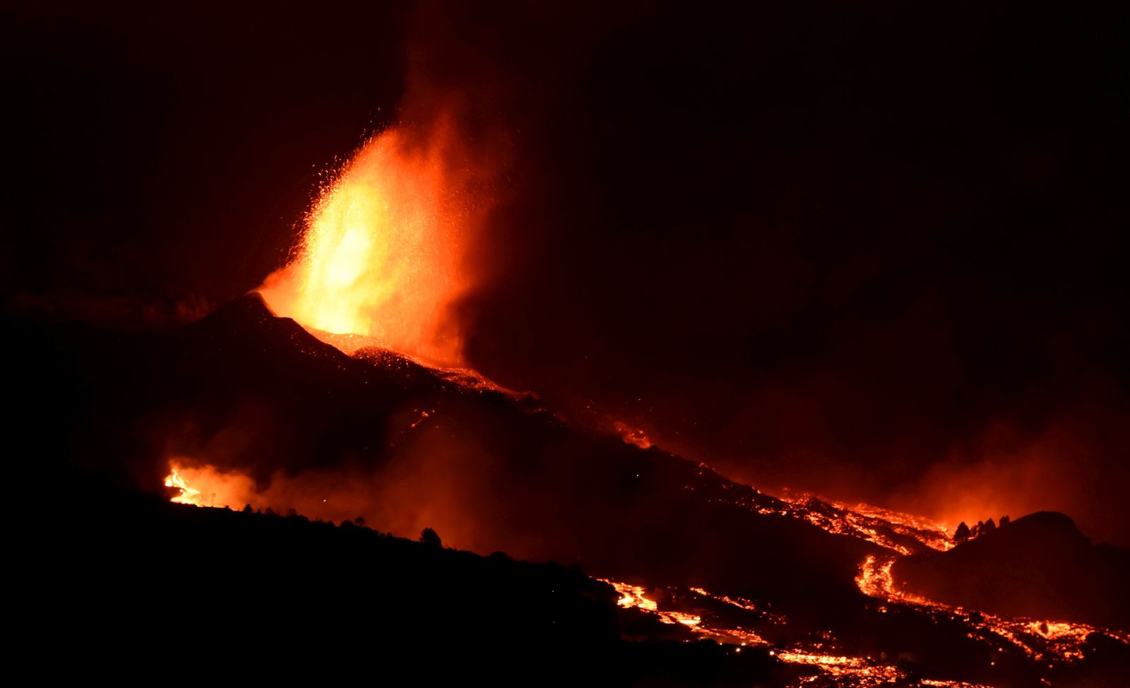 epa09478438 Lava rises up from the new volcano in Tacanade, La Palma, Canary islands, Spain, 20 September 2021.  The 'Cumbre Vieja' volcano began to erupt in Montana Rajada in the municipality of El Paso on 19 September. The area had registered hundreds of small earthquakes along the week as magma pressed the subsoil on its way out, urging the regional authorities to evacuate locals before the eruption took place.  EPA/MIGUEL CALERO
