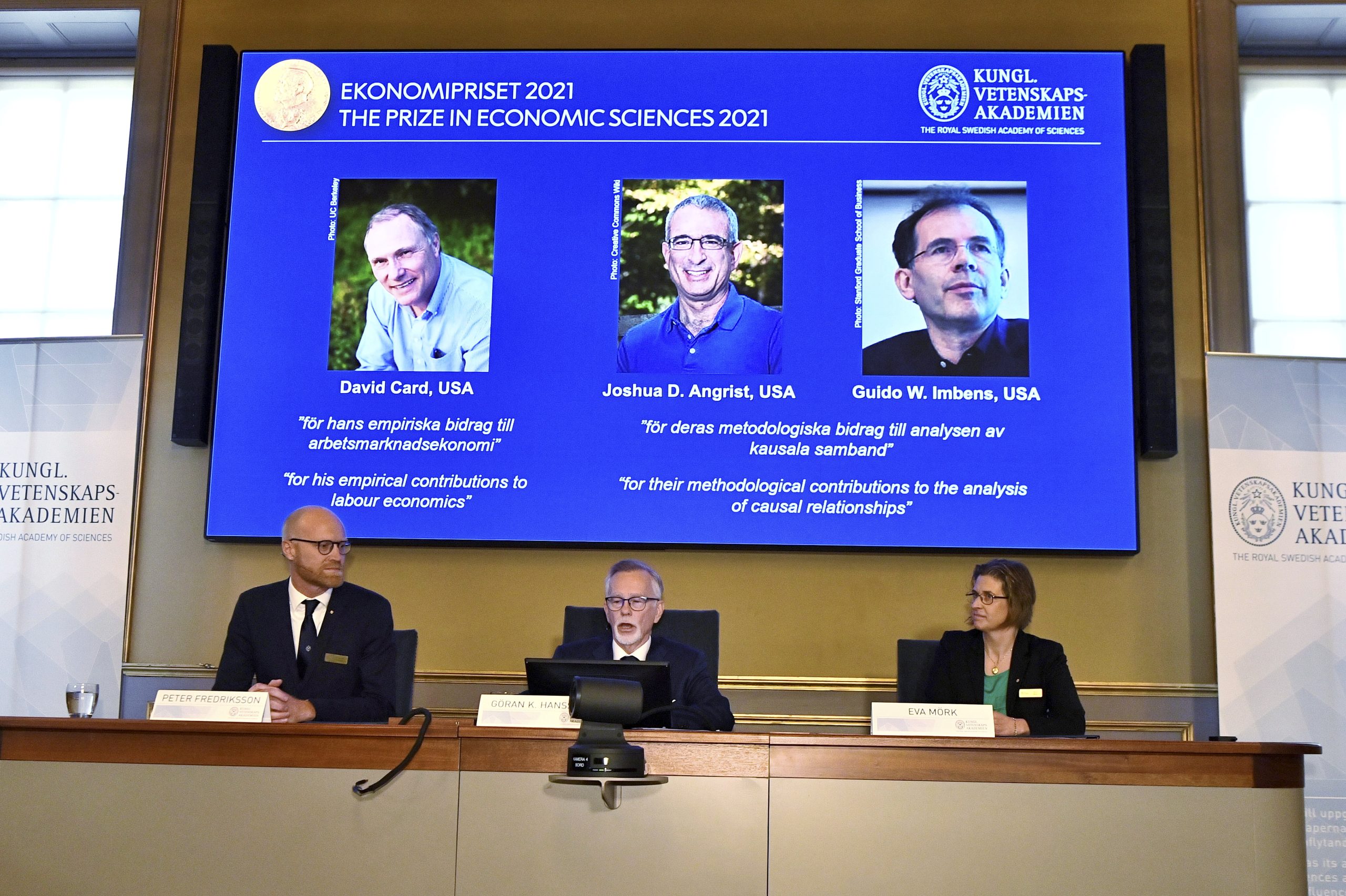 epa09518229 Goran K Hansson (C), Permanent Secretary of the Royal Swedish Academy of Sciences, Peter Fredriksson (L) and Eva Mork (R) members of the Royal Swedish Academy of Sciences, announce the Sveriges Riksbank Prize in Economic Sciences in Memory of Alfred Nobel 2021, during a press conference at the Royal Swedish Academy of Sciences in Stockholm, Sweden, 11 October 2021. L-R on screen David Card, University of California, Berkeley, USA, Joshua D. Angrist, Massachusetts Institute of Technology, Cambridge, USA and Guido W. Imbens, Stanford University, USA, are awarded the prize.  EPA/Claudio Bresciani SWEDEN OUT SWEDEN OUT