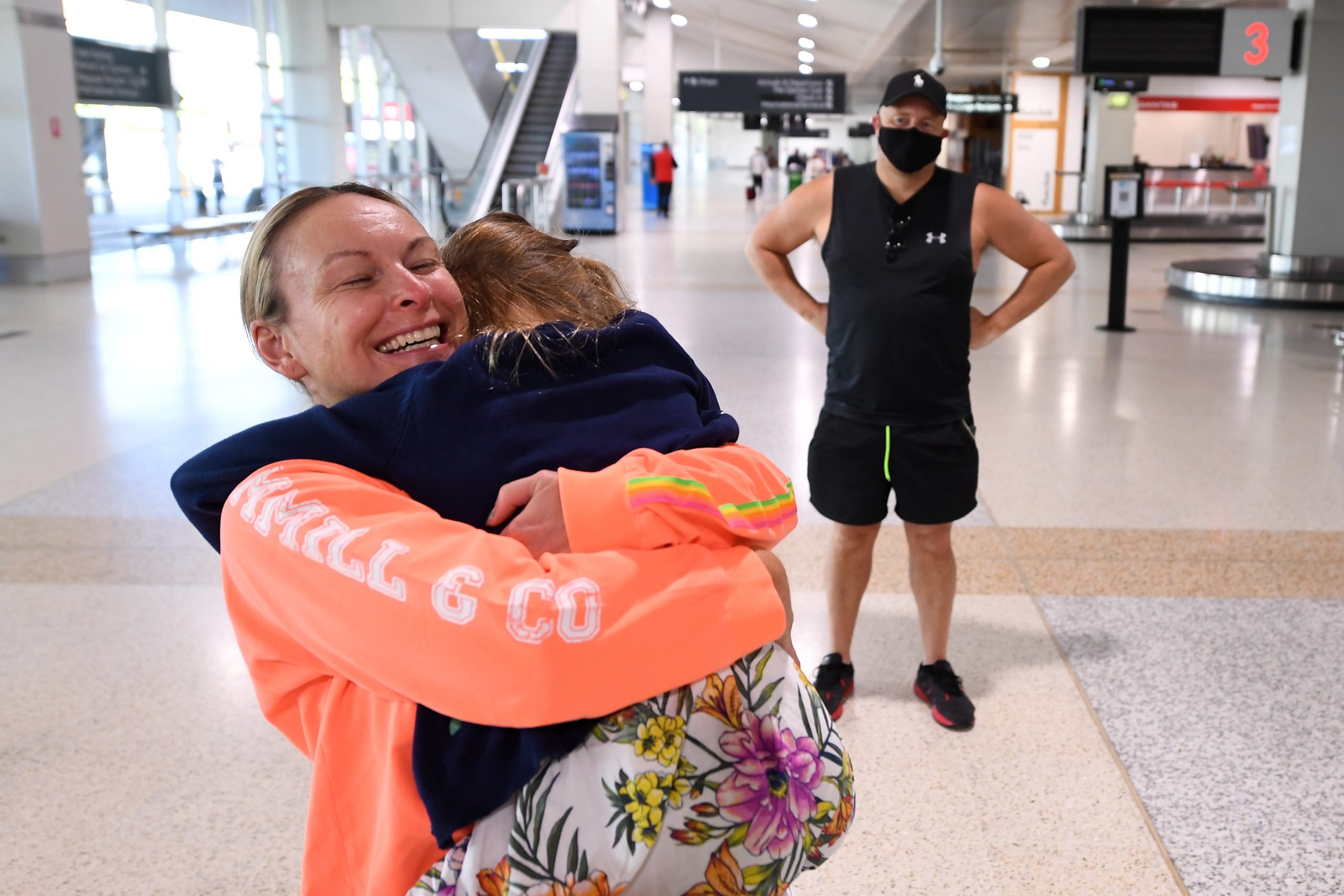 epa09533867 Melanie (L) and her daughter are reunited after spending two months apart after Melanie returned on flight QF427 at the Qantas Domestic Arrivals terminal, at Melbourne Airport, in Melbourne, Victoria, Australia, 20 October 2021. Domestic flights between Victoria and New South Wales (NSW) have resumed on the day with fully vaccinated travellers from NSW no longer required to isolate.  EPA/JAMES ROSS AUSTRALIA AND NEW ZEALAND OUT
