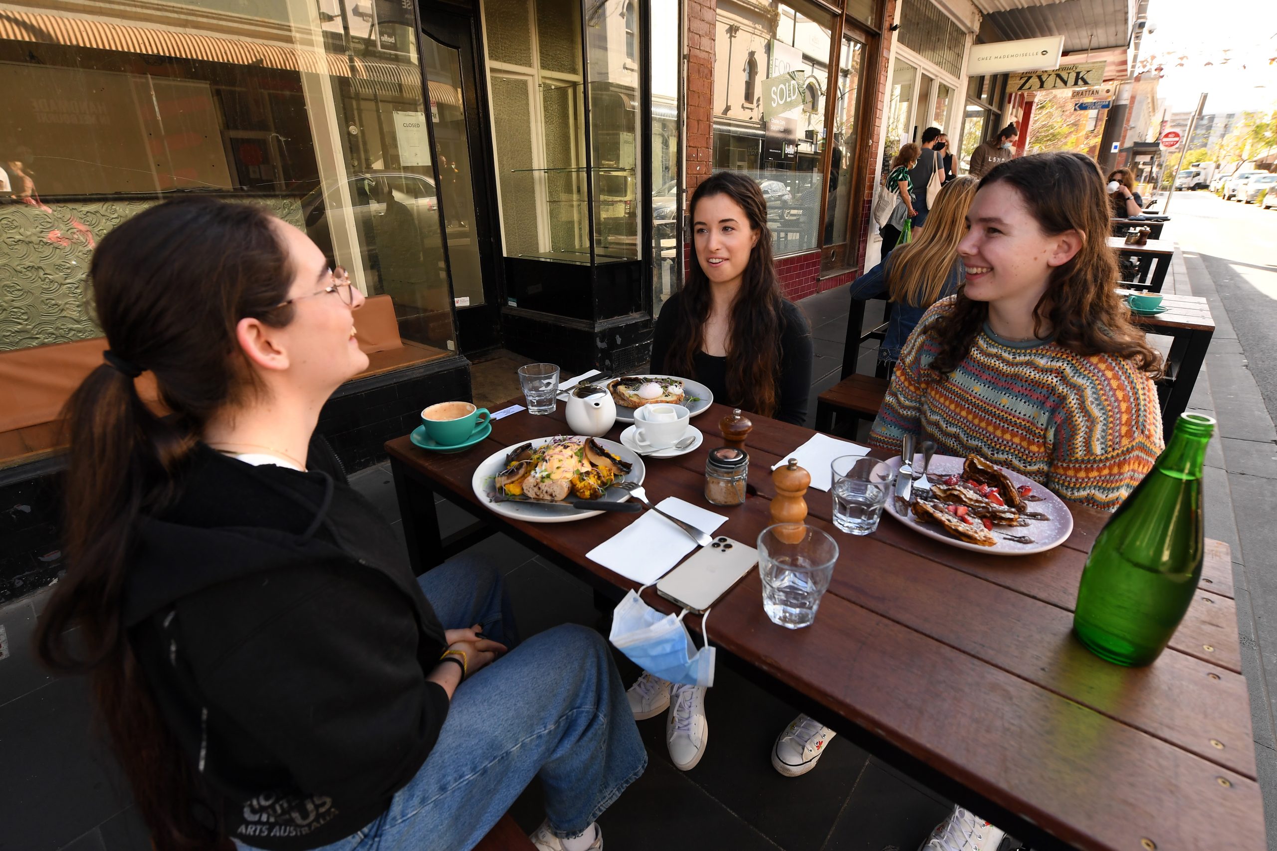 epa09538041 (L-R) Linda Richardson, Sofie Corazza and Zoe Bohlsen pose for a photo at Cafe Chez Mademoiselle in Prahran, Melbourne, Victoria, Australia, 22 October 2021. Melbourne has emerged from the world's longest lockdown, and as vaccination rates continue to rise, even more freedoms are less than two weeks away.  EPA/JAMES ROSS AUSTRALIA AND NEW ZEALAND OUT