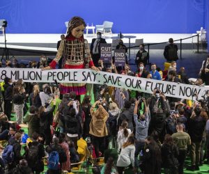 epa09572558 Delegates and participants gather around Little Amal (C), in the Hydro during the COP26 UN Climate Summit in Glasgow, Britain, 09 November 2021. Little Amal is the giant puppet of a 3.5 metre-tall living artwork of a young Syrian refugee child on 'The Walk', travelling 8,000km in 2021 in support of refugees across Turkey, Greece, Italy, France, Switzerland, Germany, Belgium and the UK to focus attention on the urgent needs of young refugees. The 2021 United Nations Climate Change Conference (COP26) runs from 31 October to 12 November 2021 in Glasgow.  EPA/ROBERT PERRY