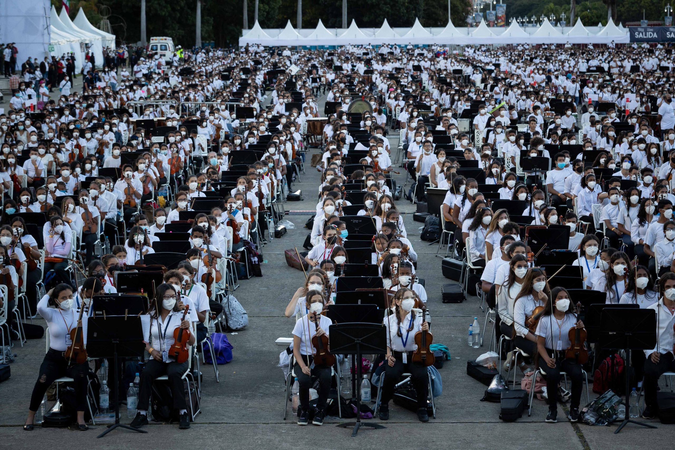 epa09581015 Thousands of musicians participate in the concert 'Venezuela, the largest orchestra in the world', in the honor yard of the Military Academy of Caracas; in Caracas, Venezuela, 13 November 2021. The System of Children and Youth Orchestras of Venezuela performed a concert with more than 12,000 musicians in an attempt to seek the Guinness World Record with the 'largest orchestra in the world' performing the Slavic March by Russian composer Pyotr Ilyich Tchaikovsky.  EPA/RAYNER PENA R.