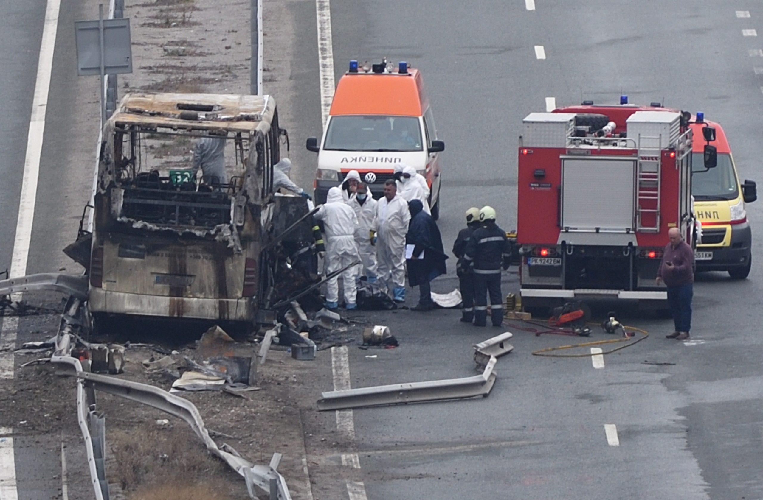 epa09598882 Fire fighters, police officers and investigators inspect the wreckage of a North Macedonia-registered bus that caught fire after crashing along a highway, killing at least 45 people, near the village of Bosnek, Bulgaria, 23 November 2021.  EPA/VASSIL DONEV