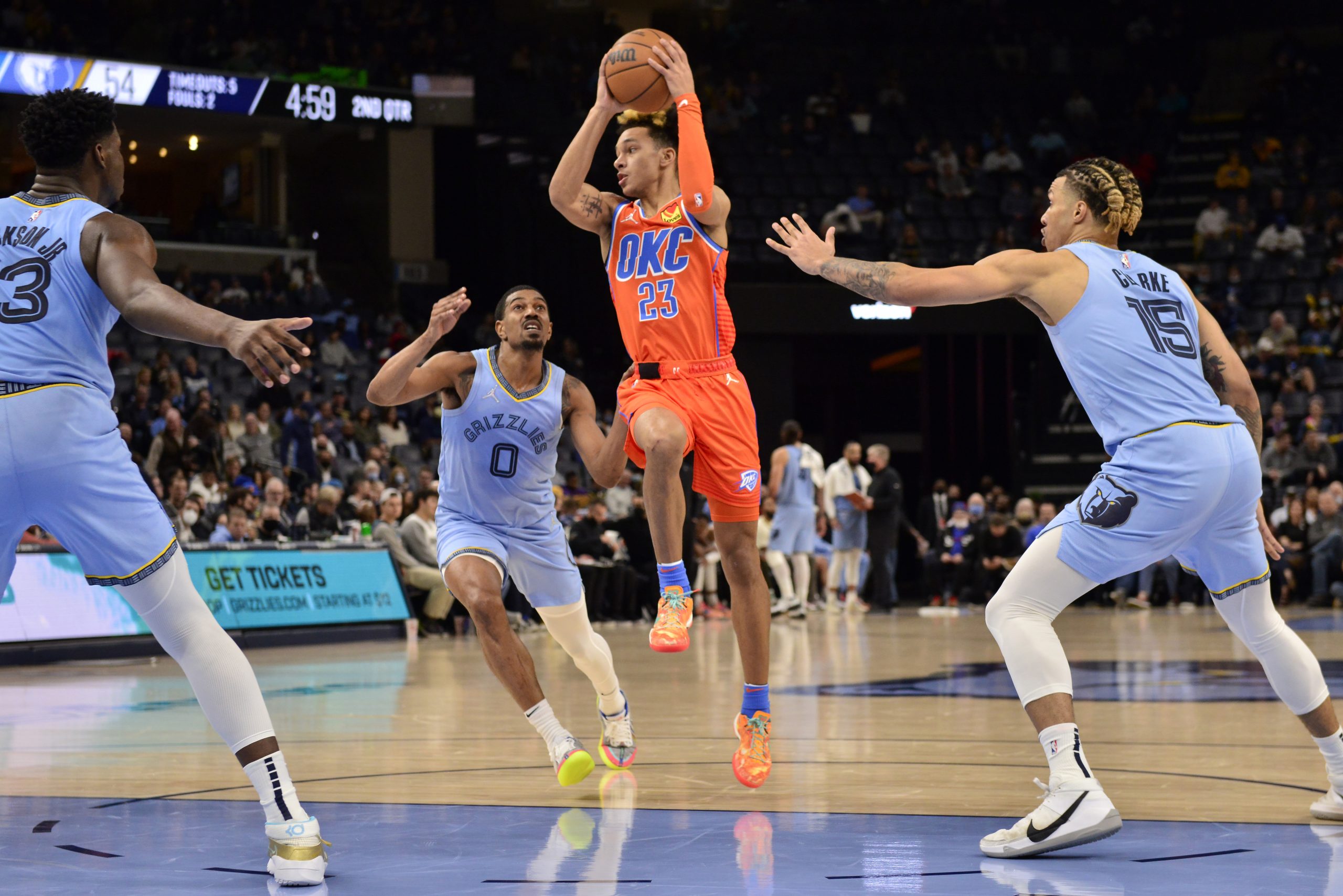 Oklahoma City Thunder guard Tre Mann (23) handles the ball between Memphis Grizzlies guard De'Anthony Melton (0) and forward Brandon Clarke (15) in the first half of an NBA basketball game Thursday, Dec. 2, 2021, in Memphis, Tenn. (AP Photo/Brandon Dill)