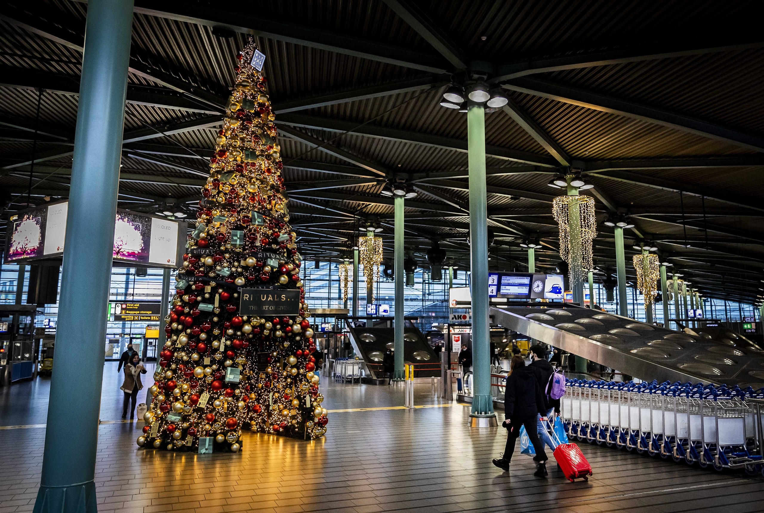 epa09612537 People at Schiphol Airport wear face masks as they walk in a seasonal decorated terminal of the airport near Amsterdam, The Netherlands, 30 November 2021. Travelers from South Africa are tested for the Coronavirus Omicron variant upon arrival in a specially designed test lane at the Schiphol airport, The Netherlands, 30 November 2021. It was decided to set up the test street after the so-called Omicron variant of the coronavirus was found in southern Africa.  EPA/REMKO DE WAAL