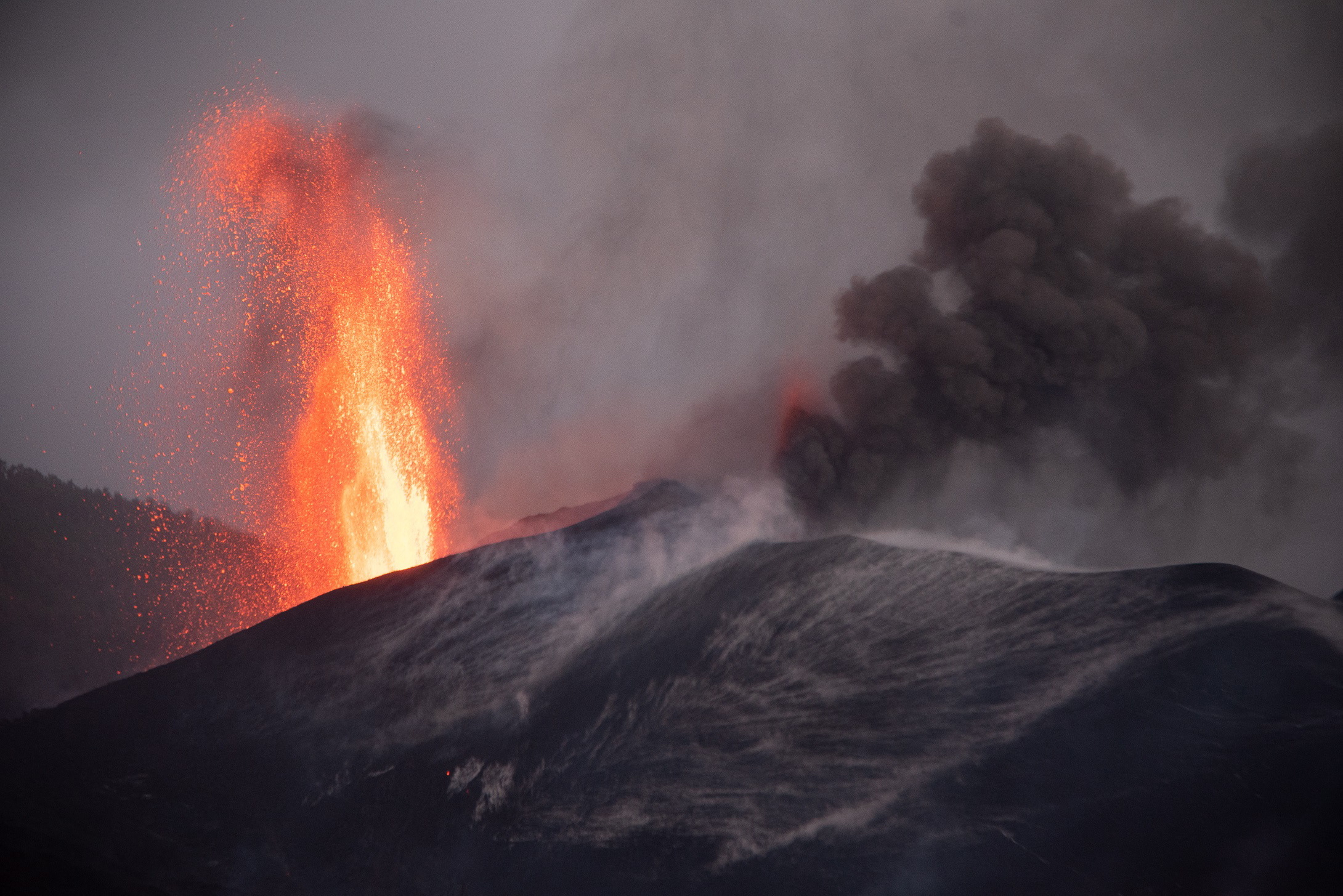 epa09615066 Smoke and lava rise from the new vent of the Cumbre Vieja volcano in El paso, La Palma, Canary Islands, Spain, 01 December 2021. A new vent appeared early morning 28 November.  EPA/Miguel Calero