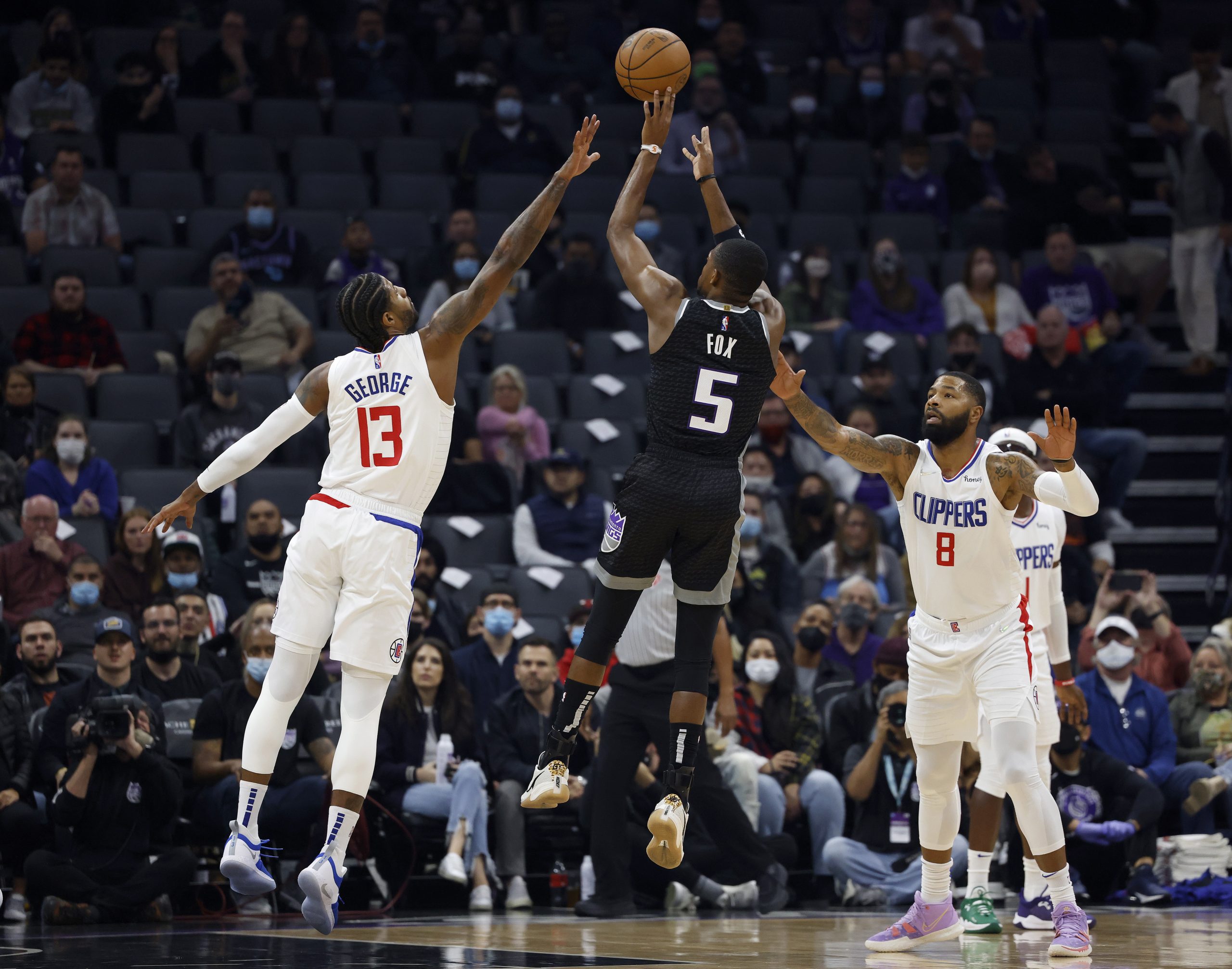 epa09622876 Sacramento Kings guard De'Aaron Fox (C) shoots a three point basket over LA Clippers guard Paul George (L) as LA Clippers forward Marcus Morris Sr. (R) looks on during the first half of their NBA game at the Golden 1 Center in Sacramento, California, USA, 04 December 2021.  EPA/JOHN G. MABANGLO  SHUTTERSTOCK OUT