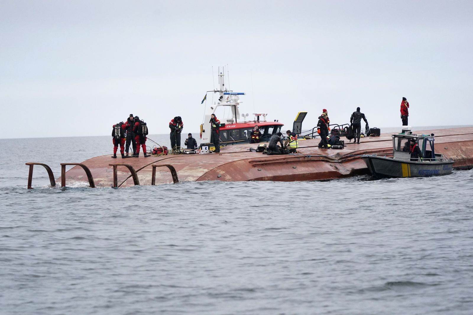 epa09640210 A view of Sea rescue members over the hull of the capsized Danish cargo ship Karin Hoej after it collided with the British cargo ship Scot Carrier in the Baltic Sea, between the Swedish town of Ystad on Sweden's southern coast and the Danish island of Bornholm, 13 December 2021. According to a statement released by the Swedish Sea Rescue Society, at least two people are feared missing after two cargo ships collided in the Baltic Sea off the Swedish coast early on 13 December. The cause of the accident is yet unknown. The Karin Hoej had capsized in the accident and was upside down.  EPA/JOHAN NILSSON  SWEDEN OUT