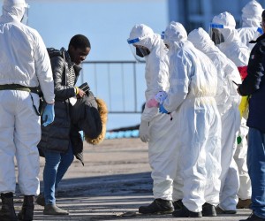 epa09655733 A migrant is assisted by Italian authorities after disembarking from the rescue vessel Sea-Eye 4 in the port of Pozzallo, in the province of Ragusa, Sicily Island, southern Italy, 24 December 2021. The rescue ship Sea-Eye 4, of the German non-governmental organization (NGO) Sea-Eye, with 214 migrants on board rescued during various operations carried out in recent days in the Mediterranean Sea, docked in the Sicilian port of Pozzallo.  EPA/CARMELO IMBESI