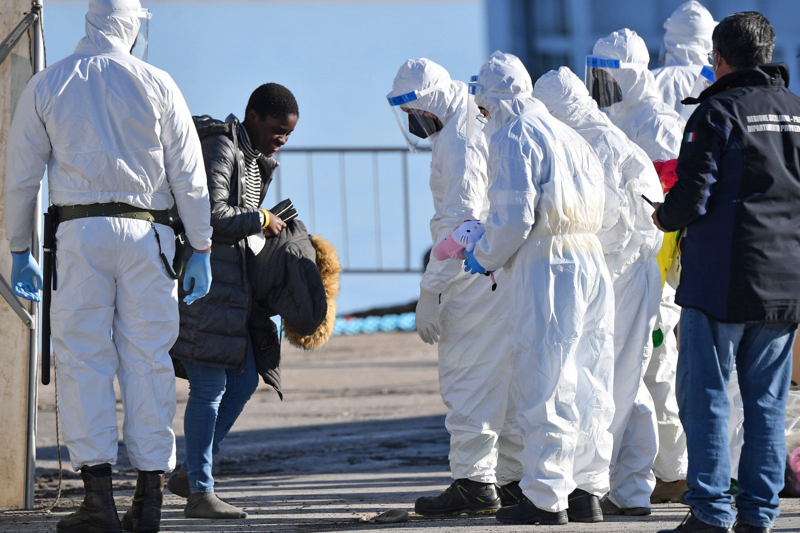 epa09655733 A migrant is assisted by Italian authorities after disembarking from the rescue vessel Sea-Eye 4 in the port of Pozzallo, in the province of Ragusa, Sicily Island, southern Italy, 24 December 2021. The rescue ship Sea-Eye 4, of the German non-governmental organization (NGO) Sea-Eye, with 214 migrants on board rescued during various operations carried out in recent days in the Mediterranean Sea, docked in the Sicilian port of Pozzallo.  EPA/CARMELO IMBESI