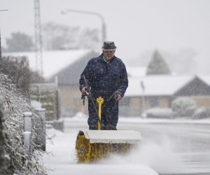 epa09654953 Joergen Stoltenborg sweeps snow away on Faelledvej in Fredericia, Jutland, Denmark, 23 December 2021.  EPA/Claus Fisker DENMARK OUT