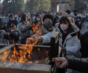 epa09662333 People gather to burn incense sticks while praying for good wishes on New Year's Day at the Yonghegong Lama Temple in Beijing, China, 01 January 2022. Many cities in China canceled New Year's Eve celebrations amid rising concerns over the coronavirus disease (COVID-19) pandemic.  EPA/WU HONG
