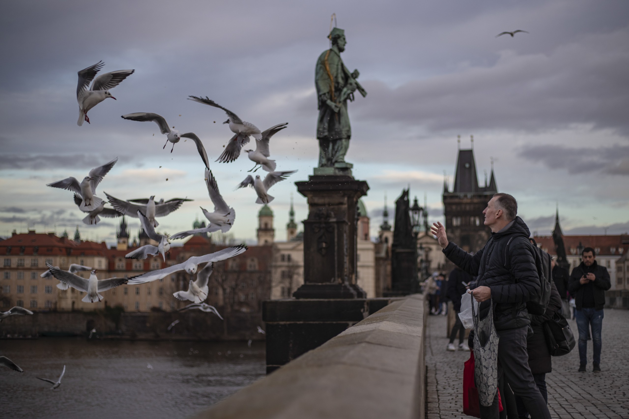 epa09664912 A man feeds gulls on Charles Bridge in Prague, Czech Republic, 03 January 2022.  Since the start of the pandemic in the Czech Republic March 2021, tests have confirmed more than 2,483,762 new cases of Covid-19. So far, 36,255 people have died with Covid-19, according to Czech Health Ministry.  EPA/MARTIN DIVISEK
