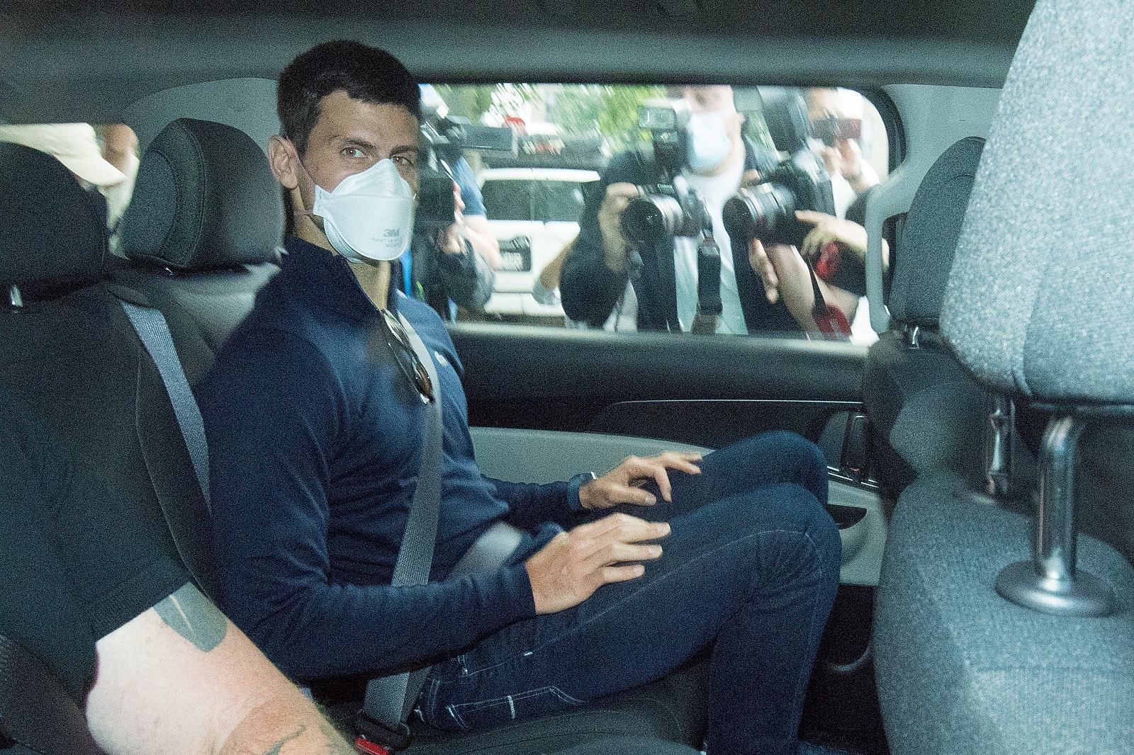epa09688461 Serbian tennis player Novak Djokovic (C) departs from the Park Hotel government detention facility before attending a court hearing at his lawyers office in Melbourne, Australia, 16 January 2022. Novak Djokovic still faces uncertainty as to whether he can compete in the Australian Open, despite being announced in the tournament draw.  EPA/JAMES ROSS NO ARCHIVING AUSTRALIA AND NEW ZEALAND OUT