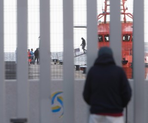 epa09710755 A person watches the arrival of migrants at Puerto del Rosario harbor in Fuerteventura, Canary Islands, Spain, 26 January 2022. A group of 32 migrants was rescued by a Sea Rescue crew while traveling in a small boat close to Lanzarote island and then transferred to the neighboring island of Fuerteventura, as Lanzarote's facilities are overcrowded. Some 409 migrants were rescued in the last 24 hours in the Canary Islands.  EPA/Carlos de Saa