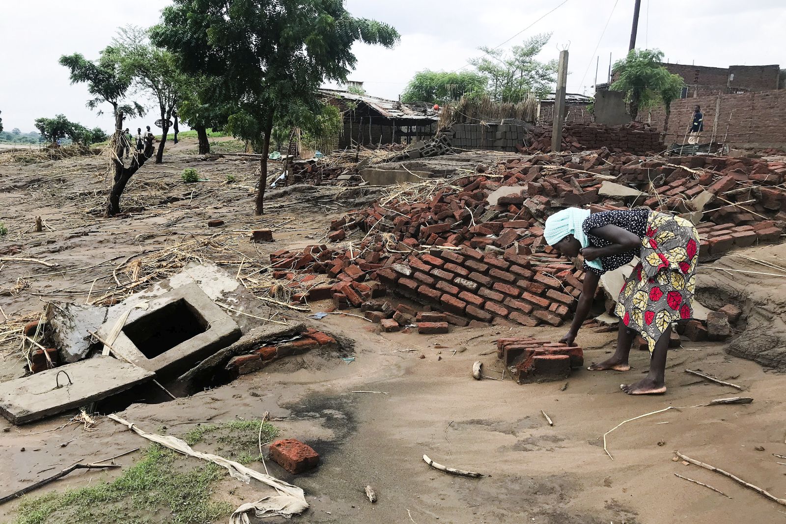 epa09711806 A woman looks for her belongings, after the Tropical Storm Ana hit the district of Tete, Mozambique, 27 January 2022. The number of deaths caused by Tropical Storm Ana in Mozambique has risen to 20 people according to data from local authorities and civil protection, and the population lives in a trail of destruction. The storm hit the country directly between Monday and Wednesday, but despite having already weakened and moved on to other countries (Zimbabwe and Zambia), the heavy rains have fed the flow of all rivers in central and northern Mozambique, which continue to cause flooding.  EPA/ANDRE CATUEIRA