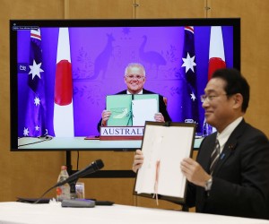 epa09668940 Japan's Prime Minister Fumio Kishida (R) and Australia's Prime Minister Scott Morrison (on video) show off signed documents during their video signing ceremony of the bilateral reciprocal access agreement at Kishida's official residence in Tokyo, Japan, 06 January 2022.  EPA/ISSEI KATO / POOL