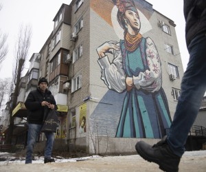 epa09725712 Locals walk in a street in front of a big mural on a building wall in the small Ukrainian city of Avdiivka not far from the pro-Russian militants-controlled city of Donetsk, Ukraine, 03 February 2022. Locals adapted to live a normal life not far from a front line amid escalation on the Ukraine - Russian border.  EPA/STANISLAV KOZLIUK