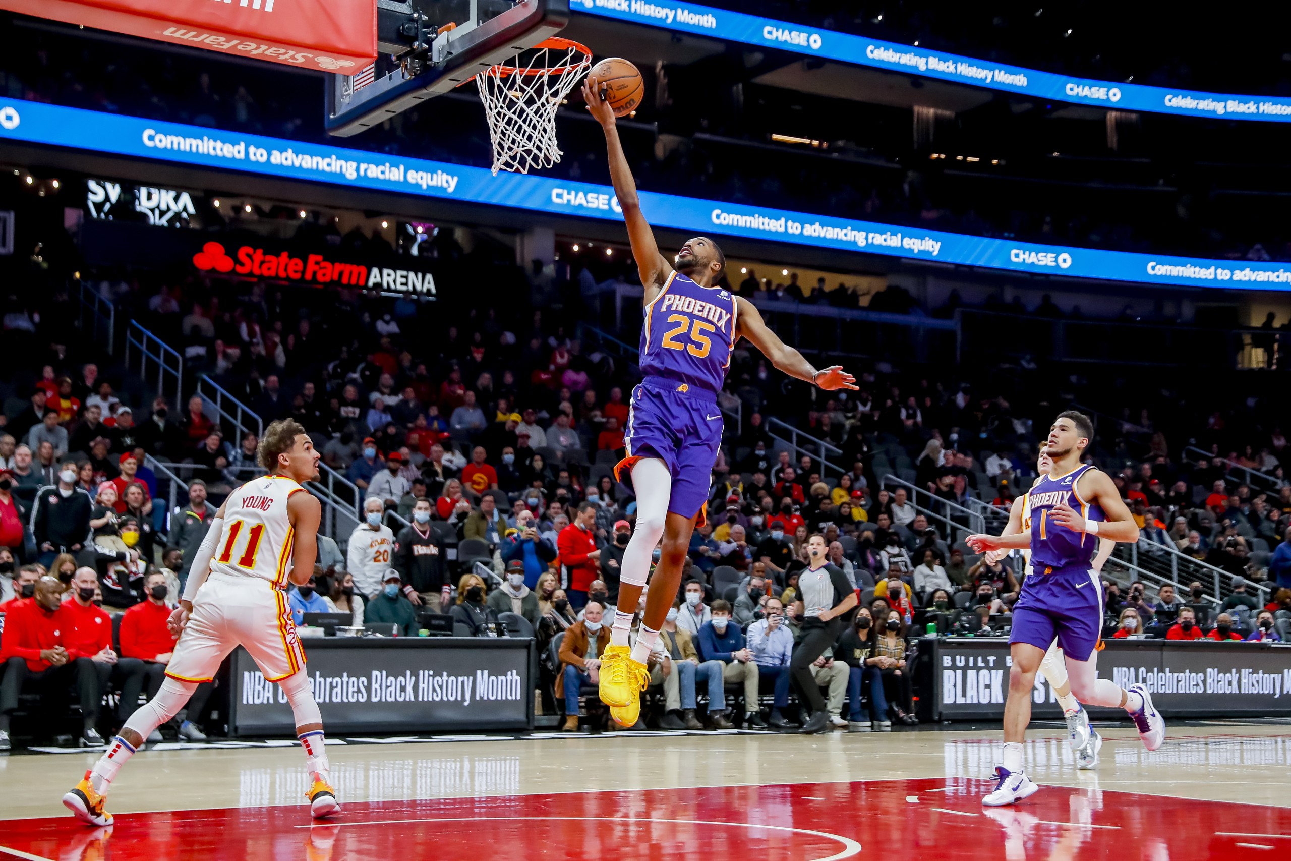 epa09726317 Phoenix Suns forward Mikal Bridges (C) shoots against Atlanta Hawks guard Trae Young (L) as Phoenix Suns guard Devin Booker (R) looks on during the first half of the NBA basketball game between the Phoenix Suns and the Atlanta Hawks at State Farm Arena in Atlanta, Georgia, USA, 03 February 2022.  EPA/ERIK S. LESSER  SHUTTERSTOCK OUT
