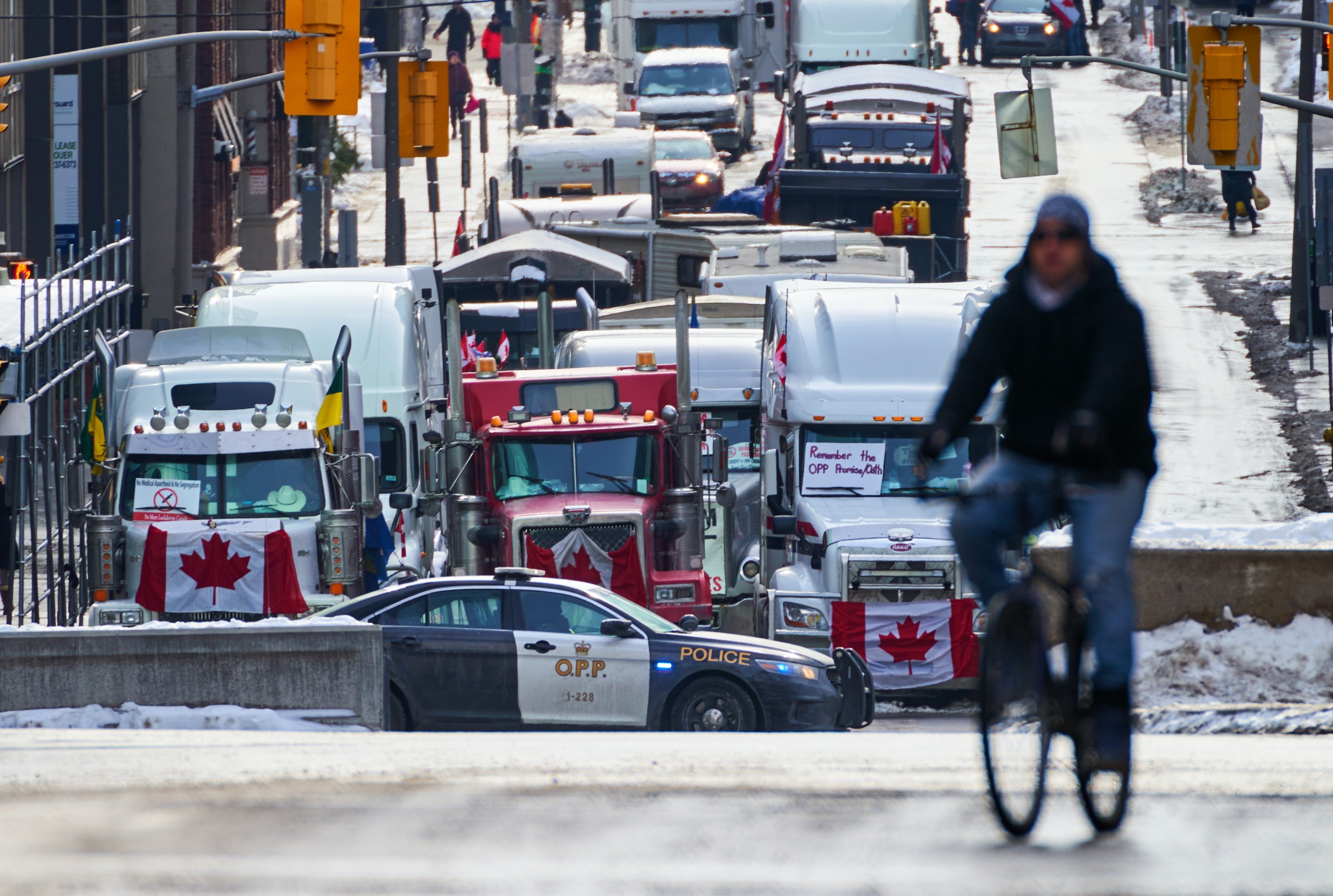 epa09741756 A person cycles past a roadblock as truckers continue to protest the vaccine mandates in in downtown Ottawa, Ontario, Canada, 09 February 2022. Since 29 January 2022, truckers are protesting against the mandate by the Canadian government that truckers be vaccinated against COVID-19 to return to Canada, and was joined by other opponents of the Canadian Prime Minister. A state of emergency was declared in the city of Ottawa on 06 February 2022 and policemen from Ottawa city, Ontario, and the Federal Royal Canadian Mounted Police (RCMP) are deployed.  EPA/ANDRE PICHETTE