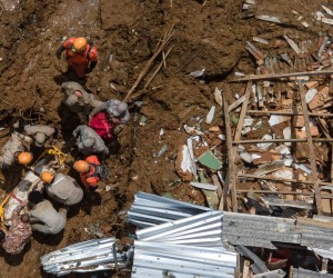 epa09764113 A photograph taken with a drone showing firefighters carrying a person killed by the landslide that has left 67 dead so far in Petropolis, Brazil, 16 February 2022. Petropolis, about 70 kilometers from Rio de Janeiro, accumulated 259 millimeters of rain in six hours in the afternoon and night of 15 February, according to civil defense sources, and a moderate amount of rainfall is also expected on 16 February.  EPA/Antonio Lacerda