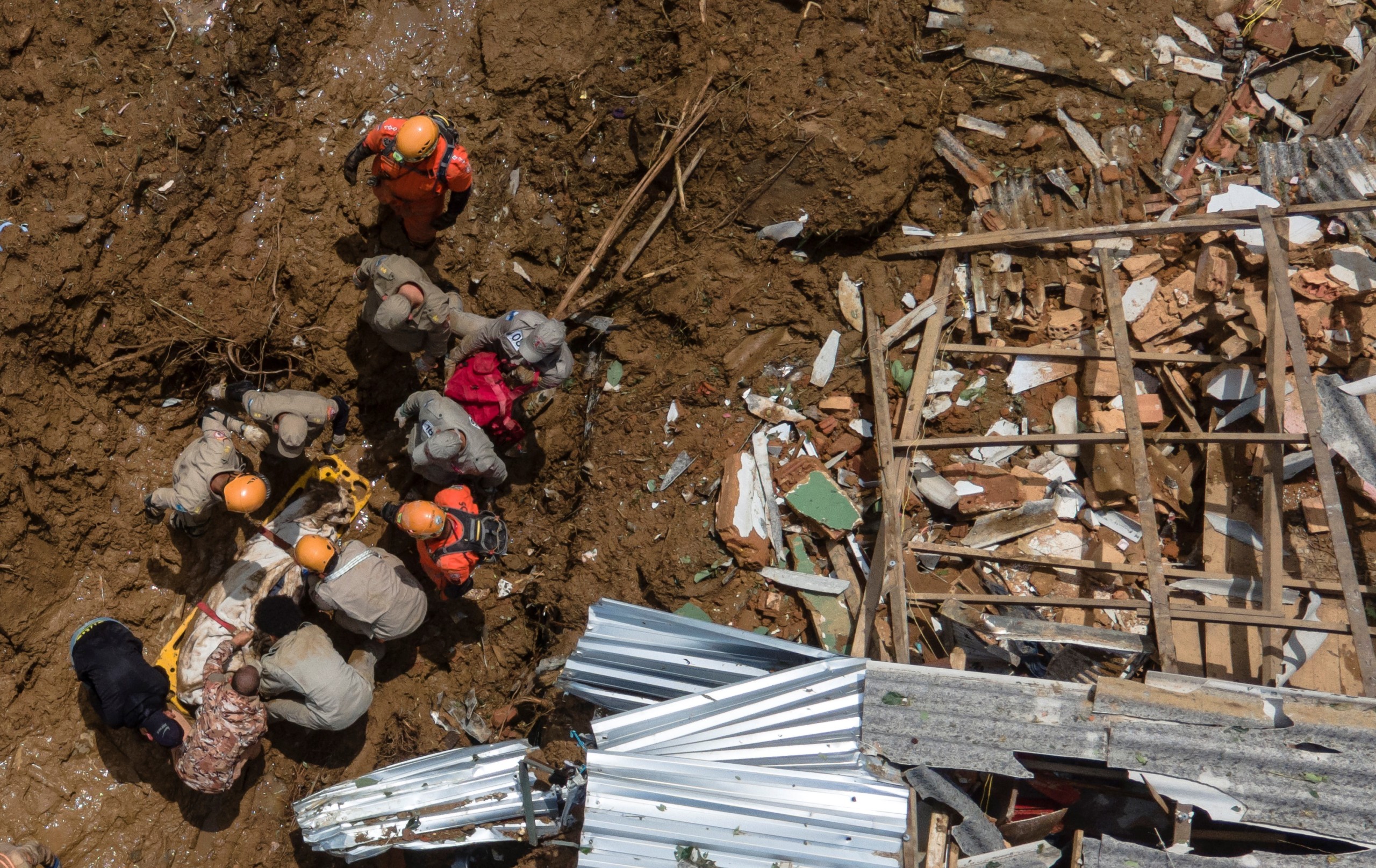 epa09764113 A photograph taken with a drone showing firefighters carrying a person killed by the landslide that has left 67 dead so far in Petropolis, Brazil, 16 February 2022. Petropolis, about 70 kilometers from Rio de Janeiro, accumulated 259 millimeters of rain in six hours in the afternoon and night of 15 February, according to civil defense sources, and a moderate amount of rainfall is also expected on 16 February.  EPA/Antonio Lacerda