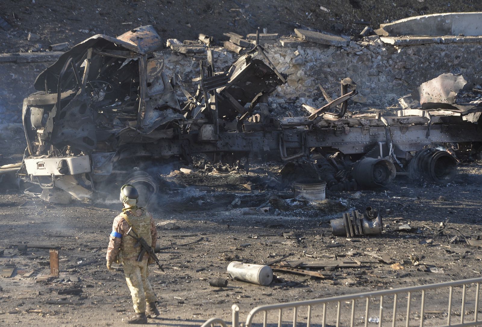 epa09786493 A Ukrainian serviceman stands near a charred vehicle after night fighting in Kiev, Ukraine, 26 February 2022. Russian troops entered Ukraine on 24 February prompting the country's president to declare martial law and triggering a series of announcements by Western countries to impose severe economic sanctions on Russia.  EPA/ANDRII NESTERENKO