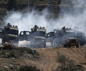 epa09769434 Israeli soldiers seek cover from tear gas thrown back by Palestinian protesters during clashes after a demonstration against Israel's settlements on the lands of Beita village near the West Bank city of Nablus, 18 February 2022. 39 Palestinians were wounded during the clashes.  EPA/ALAA BADARNEH