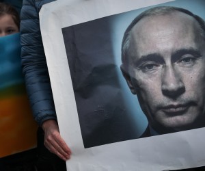epa09787717 A woman holds a Vladimir Putin portrait as she takes part in the Human Cordon for Peace in Ukraine gathered in front of Belem Presidential Palace, in Lisbon, Portugal, 26 February 2022. People all over the world held vigils and demonstrations for peace in the Ukraine and against Russian troops invading the country. Russian troops entered Ukraine on 24 February prompting the country's president to declare martial law and triggering a series of announcements by Western countries to impose severe economic sanctions on Russia.  EPA/RODRIGO ANTUNES