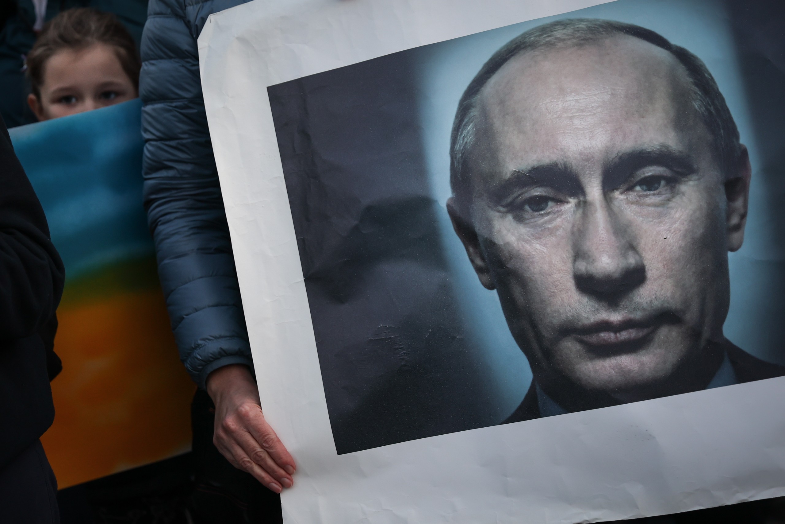 epa09787717 A woman holds a Vladimir Putin portrait as she takes part in the Human Cordon for Peace in Ukraine gathered in front of Belem Presidential Palace, in Lisbon, Portugal, 26 February 2022. People all over the world held vigils and demonstrations for peace in the Ukraine and against Russian troops invading the country. Russian troops entered Ukraine on 24 February prompting the country's president to declare martial law and triggering a series of announcements by Western countries to impose severe economic sanctions on Russia.  EPA/RODRIGO ANTUNES