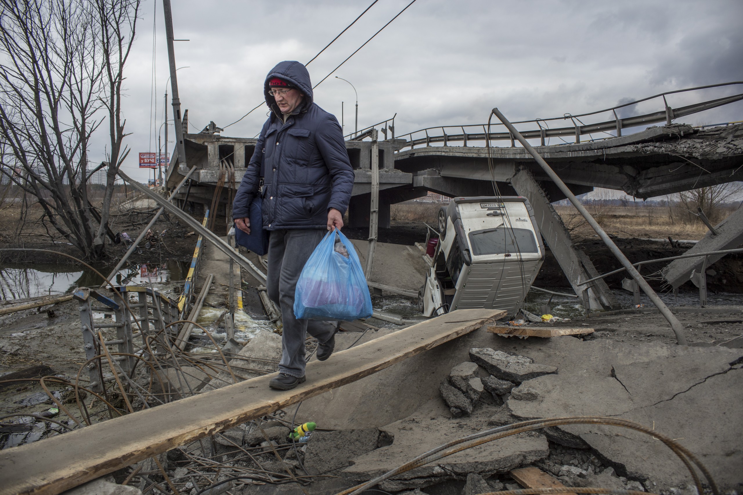 epa09806184 Civilians cross amid rubble of a damaged bridge in the Irpin city near from Kyiv (Kiev), Ukraine, 06 March 2022. Russian troops began a military operation in Ukraine on 24 February leading to a massive exodus of Ukrainians to neighboring countries as well as internal displacements.  EPA/OLEKSANDR RATUSHNIAK