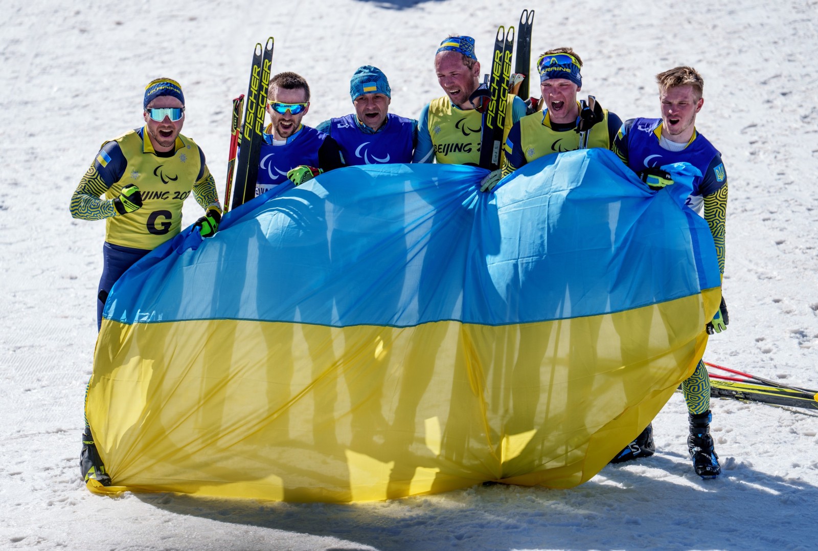 epa09809277 A handout photo made available by the Olympic Information Service shows winner Vitalii Lukianenko of Ukraine (guide Boys Babar), runner up Anatolii Kovalevskyi of Ukraine (guide Oleksandr Mukshin, and third placed Dmytro Suiarko of Ukraine (guide Oleksandr Nikonovych) celebrating after the Men's Middle Distance Vision Impaired Para Biathlon at the Zhangjiakou National Biathlon Centre during Beijing 2022 Winter Paralympic Games, Zhangjiakou, China, 08 March 2022.  EPA/Thomas Lovelock / HANDOUT  HANDOUT EDITORIAL USE ONLY/NO SALES