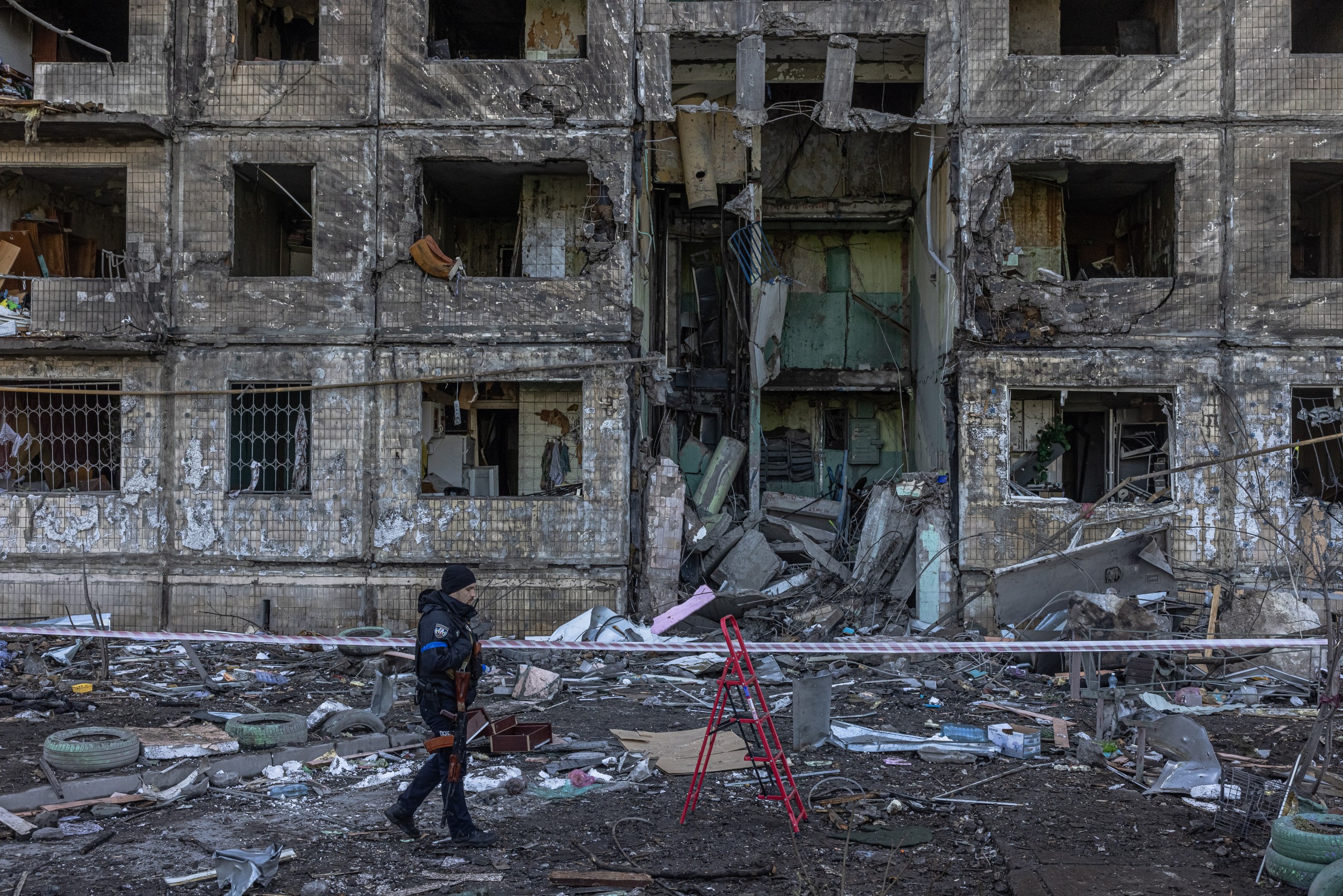 epaselect epa09824316 A Ukrainian police officer stands guard next to the residential building which was hit by the Russian artillery shelling, in the Obolon district, in Kyiv, Ukraine, 14 March 2022. At least two people reportedly have been killed after the artillery shelling. Russian troops entered Ukraine on 24 February prompting the country's president to declare martial law and triggering a series of announcements by Western countries to impose severe economic sanctions on Russia.  EPA/ROMAN PILIPEY