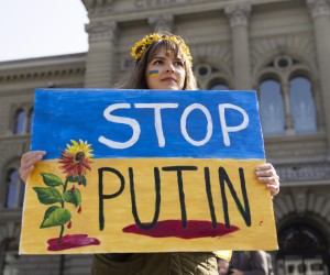 epa09835741 A Protester holds a 'Stop Putin' banner on the Bundesplatz square during a demonstration against the Russian invasion of Ukraine in front of the Swiss parliament building in Bern, Switzerland, 19 March 2022.  EPA/PETER KLAUNZER