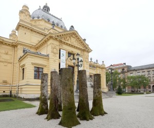 06.05.2021., Zagreb - Nova izlozbu u ciklusu "Umjetnost ispred Umjetnickog paviljona" posvecena je prisjecanju na renomiranog hrvatskog kipara Slavomira Drinkovica. rTrupci su u sustini kocka prostora koju artikulira devet hrastovih trupaca postavljenih u guste trorede po tri trupca svaki. Rijec je o formaciji kakvu je po jednoobraznom intenzitetu unutrasnjih medjuprostora mogao postaviti jedino umjetnik, nikako priroda.rZacudni ucinak proizlazi upravo iz napetosti izmedju organske prirode debala i strogo artificijelnog načina njihova tretiranja i organizacije.rPrva inacica ovog rada bila je postavljena u njemackom gradu Drezdenu 2013. godine. Photo: Patrik Macek/PIXSELL
