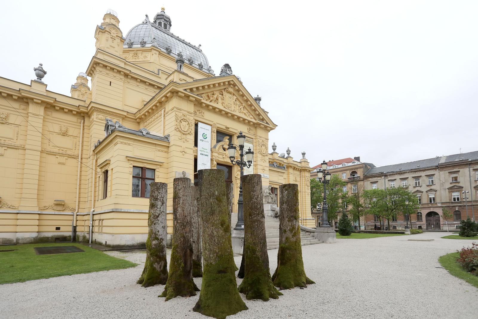 06.05.2021., Zagreb - Nova izlozbu u ciklusu "Umjetnost ispred Umjetnickog paviljona" posvecena je prisjecanju na renomiranog hrvatskog kipara Slavomira Drinkovica. rTrupci su u sustini kocka prostora koju artikulira devet hrastovih trupaca postavljenih u guste trorede po tri trupca svaki. Rijec je o formaciji kakvu je po jednoobraznom intenzitetu unutrasnjih medjuprostora mogao postaviti jedino umjetnik, nikako priroda.rZacudni ucinak proizlazi upravo iz napetosti izmedju organske prirode debala i strogo artificijelnog načina njihova tretiranja i organizacije.rPrva inacica ovog rada bila je postavljena u njemackom gradu Drezdenu 2013. godine. Photo: Patrik Macek/PIXSELL