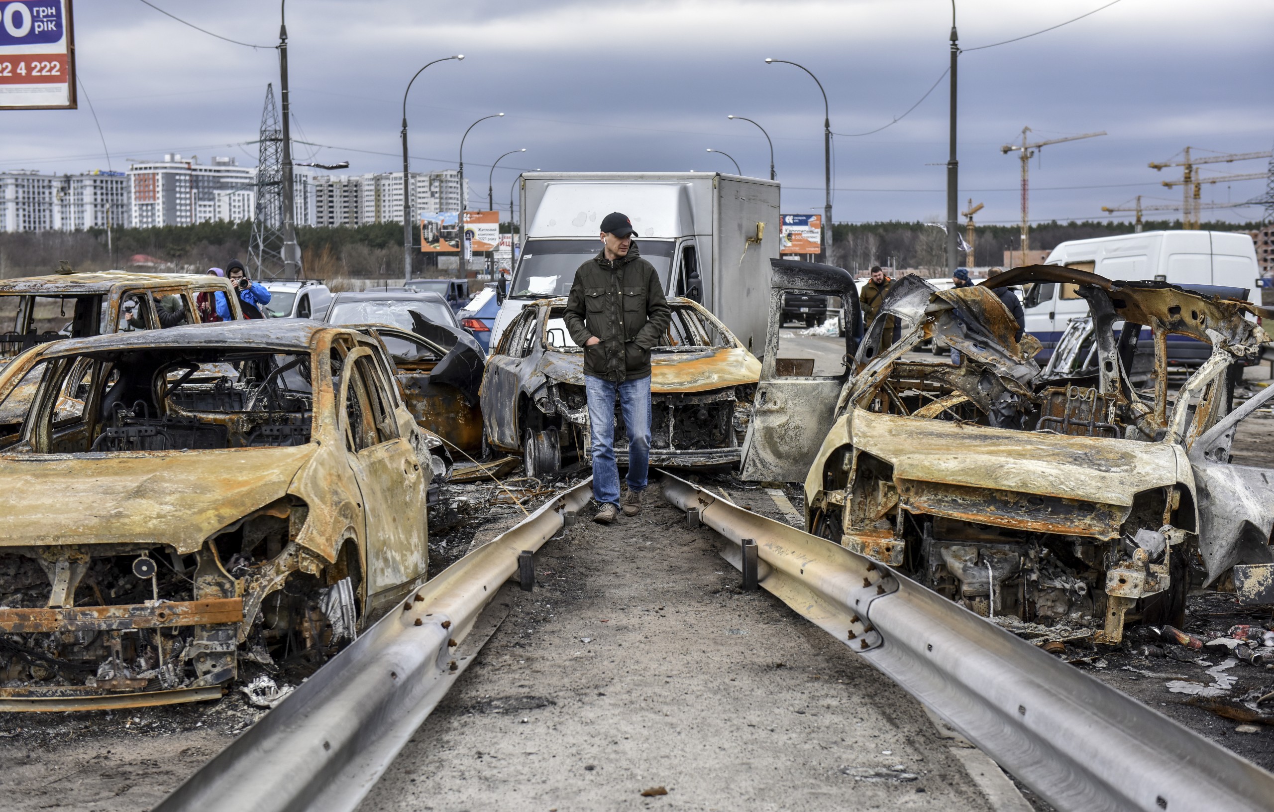 epa09873519 A man walks past burnt cars on a damaged bridge near the recaptured city of Irpin, Ukraine, 06 April 2022. Ukrainian forces have recently recaptured from the Russian army some cities and villages in the outskirts of Kyiv.  EPA/OLEG PETRASYUK