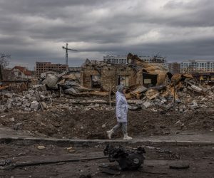 epa09874817 A woman walks past destroyed houses on the street, in Bucha, the town which was retaken by the Ukrainian army, northwest of Kyiv, Ukraine, 06 April 2022. Hundreds of tortured and killed civilians have been found in Bucha and other parts of the Kyiv region after the Russian army retreated from those areas. Russian troops entered Ukraine on 24 February resulting in fighting and destruction in the country, and triggering a series of severe economic sanctions on Russia by Western countries.  EPA/ROMAN PILIPEY