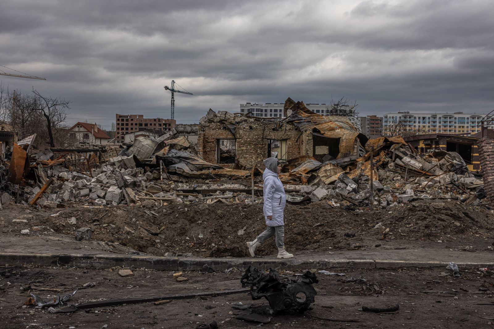 epa09874817 A woman walks past destroyed houses on the street, in Bucha, the town which was retaken by the Ukrainian army, northwest of Kyiv, Ukraine, 06 April 2022. Hundreds of tortured and killed civilians have been found in Bucha and other parts of the Kyiv region after the Russian army retreated from those areas. Russian troops entered Ukraine on 24 February resulting in fighting and destruction in the country, and triggering a series of severe economic sanctions on Russia by Western countries.  EPA/ROMAN PILIPEY