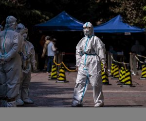 epa09885371 Security members and police in protective gear stand in a residential community under lockdown in Shanghai, China, 12 April 2022. Shanghai authorities announced, on 12 April, the release of some residential areas without coronavirus cases from Covid-19 lockdown, while the majority are still closed with residents reportedly complaining about food shortages.  EPA/ALEX PLAVEVSKI